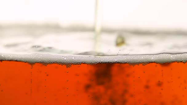 Close-up van gieten donker bier met bubbels in glas - Video