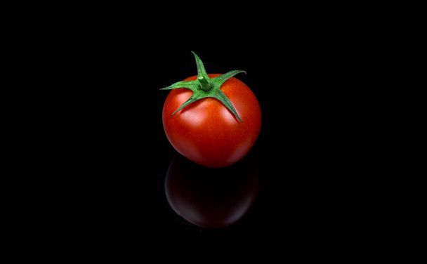 Fresh cherry tomato single on black background - Fotó, kép