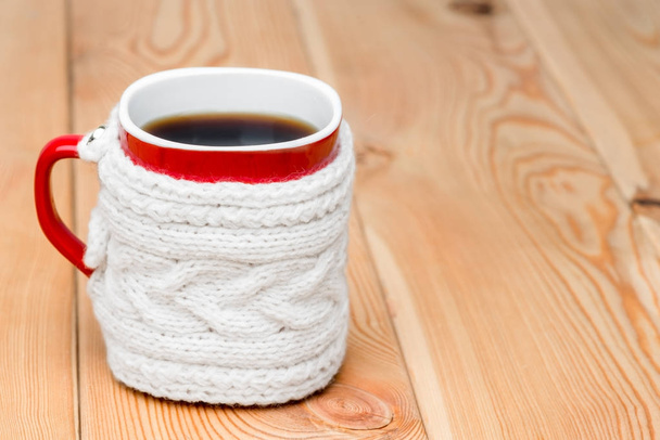червона чашка в білому в'язаному светрі з гарячим чаєм на дерев'яних дошках
 - Фото, зображення