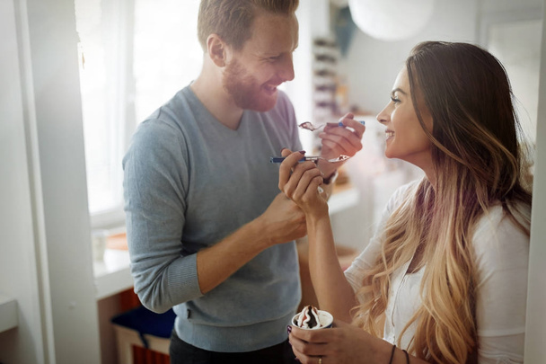 Couple having fun and laughing at home while eating ice cream - Photo, image