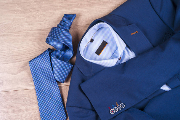 set di abiti classici da uomo - abito blu, camicie, scarpe marroni, cintura e cravatta su sfondo di legno. - Foto, immagini