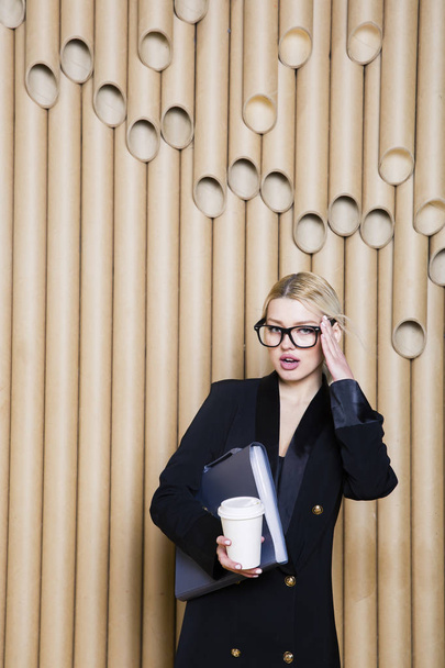 Beautiful amazed blonde business woman in black dress and glasses with coffee mug. - Foto, afbeelding