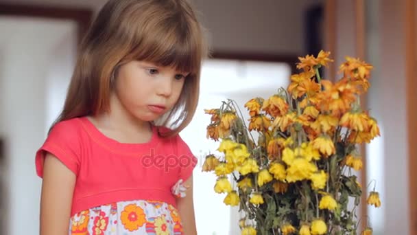 trauriges kleines Mädchen blickt auf welke Blumen - Filmmaterial, Video