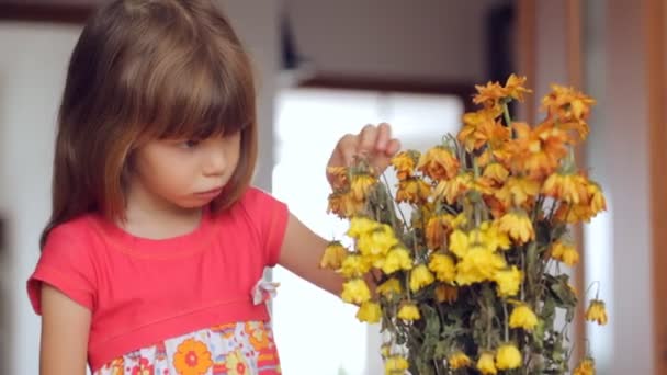 trauriges kleines Mädchen blickt auf welke Blumen - Filmmaterial, Video