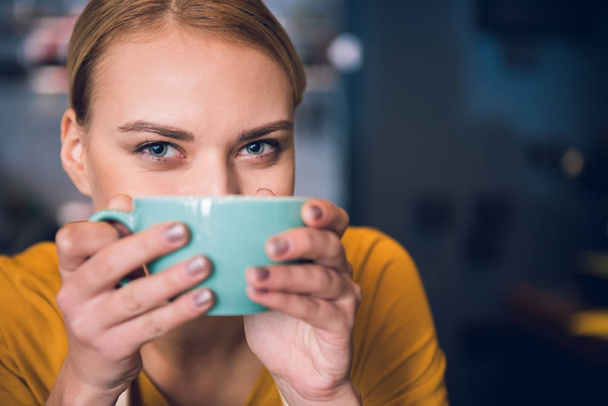Cheerful girl keeping mug near mouth - Фото, изображение