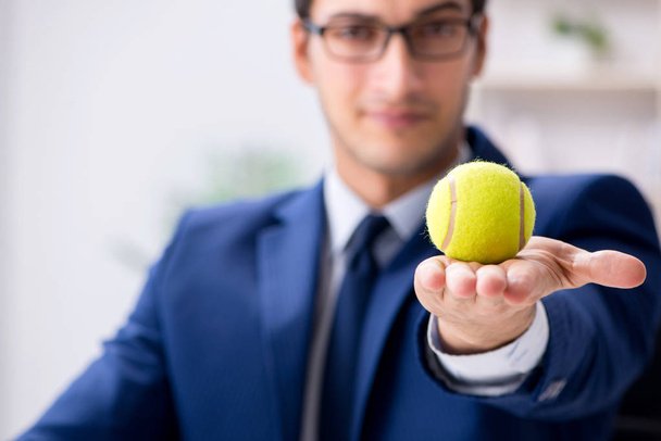 Jonge zakenman met tennisbal aan het werk - Foto, afbeelding