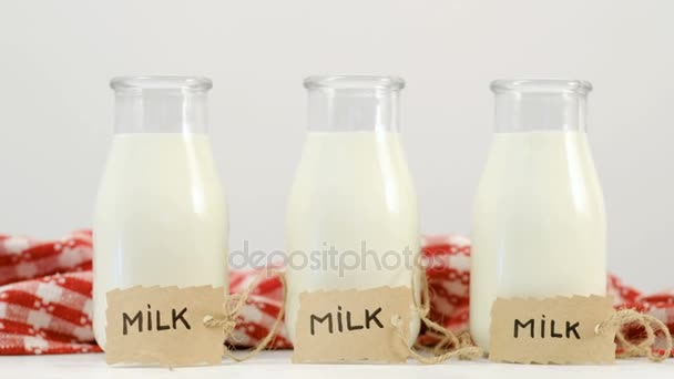 three milk bottles white red background slide shot - Metraje, vídeo