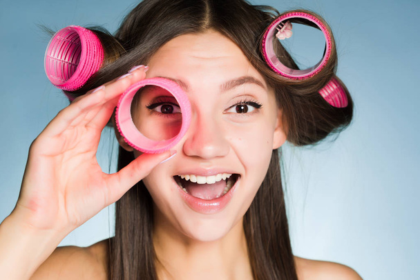 happy smiling girl wants a beautiful hairstyle, holds in her hand curlers - Foto, immagini