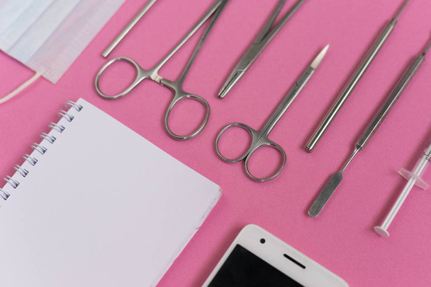 on the pink surface are dental appliances, a smartphone and a notebook - Photo, Image