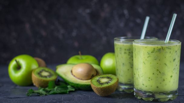Two glass glass filled with the smoothie of avocado on wooden table with fruits. Diet vegetarian food. - Foto, imagen