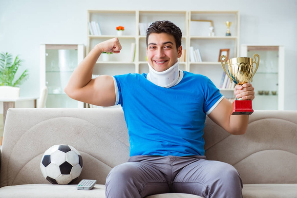 Man with neck injury watching football soccer at home - Photo, Image