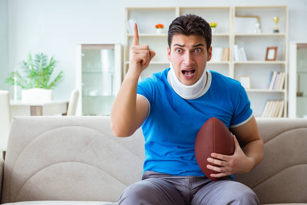 Boynu yaralanmış bir adam evde Amerikan futbolu seyrediyor. - Fotoğraf, Görsel