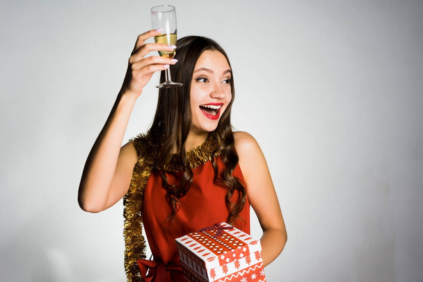 happy beautiful girl celebrates the new year 2018, holds in her hand a glass of champagne and a gift - Fotografie, Obrázek