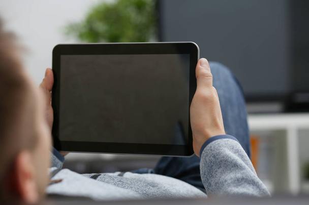 Male hand holds tablet in home setting while - Foto, Imagem