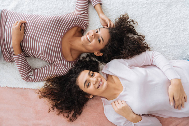Beautiful girls beaming while relaxing on bed - Фото, зображення
