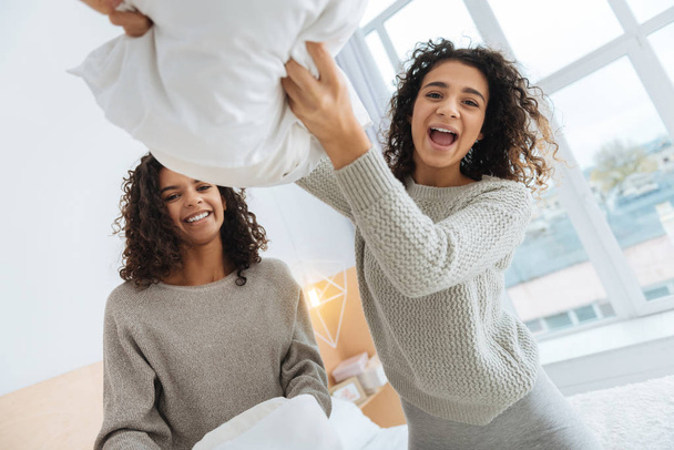 Beautiful sibling grinning broadly during pillow fight - Photo, Image