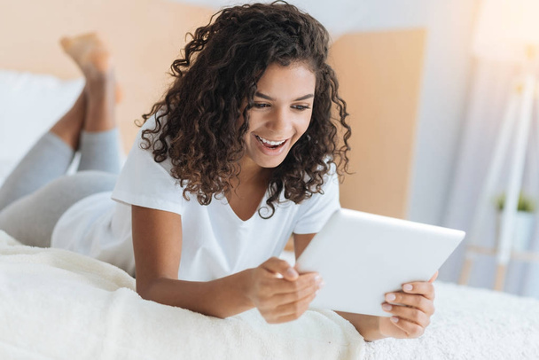 Extremely happy girl smiling while looking at tablet computer - Foto, Imagem