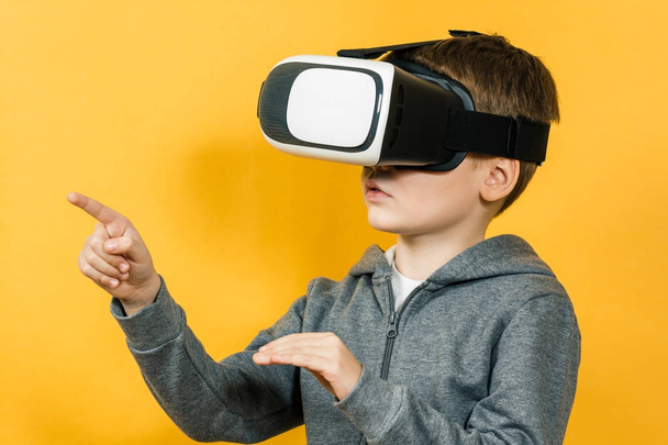 Boy with a headset of virtual reality. Innovative technology. On an orange background. - Foto, Imagem