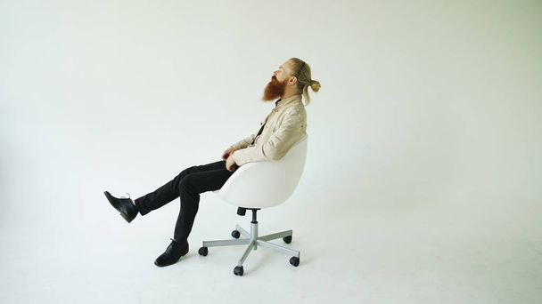 Smiling bearded man turning on swivel office chair on white background - Photo, image