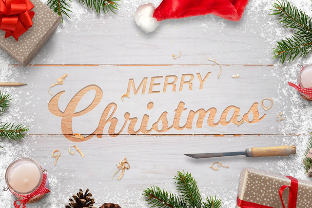 Χριστούγεννα σκάλισμα σε λευκή ξύλινη σανίδα. Καλά Χριστούγεννα χαιρετισμό κείμενο που περιβάλλεται με διακοσμήσεις. - Φωτογραφία, εικόνα
