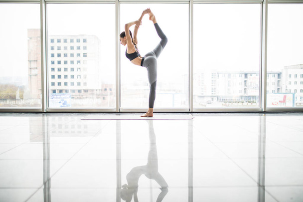 Jeune jolie femme faisant de l'exercice d'étirement sur tapis de yoga. Concept de conditionnement physique, sport, entraînement et mode de vie
. - Photo, image