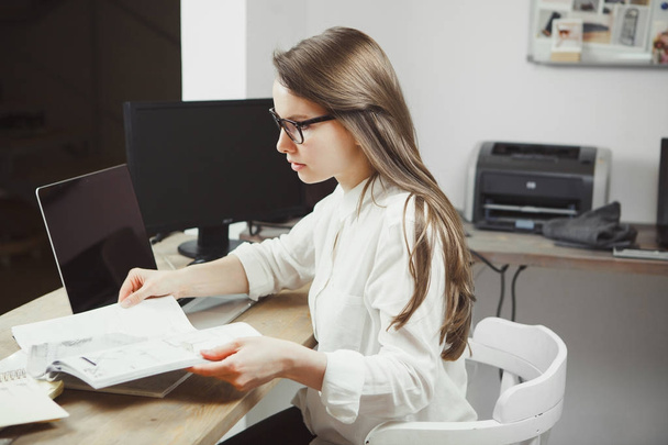 Serious woman in glasses work with papers near computer - Foto, imagen