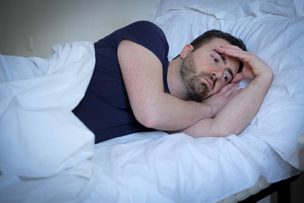 Smutný a naštvaný muž snaží spát v posteli - Fotografie, Obrázek