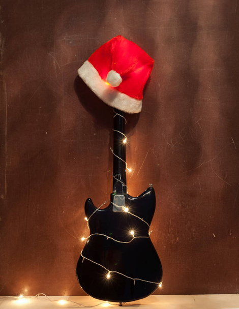 Chapeau de Noël rouge sur guitare basse électrique noire
. - Photo, image