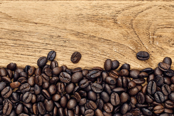 Granos de café negro se encuentran en una mesa de madera marrón, fondo
  - Foto, imagen