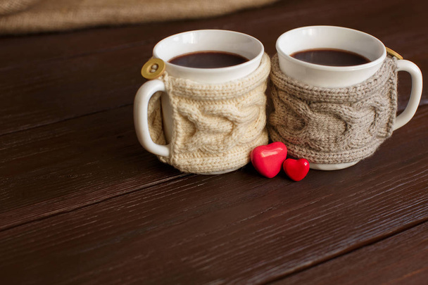 Love background, two cups of coffee with knitted cup holder near two hearts for valentine 's day. Копировать пространство для любовного текста
 - Фото, изображение
