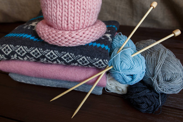 Tricot maison, chandails tricotés colorés près du chapeau rose et des boules de fil. Tricot fait main
 - Photo, image