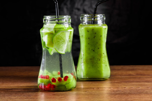 Refreshing drink from kiwi, green apple, lime, mint and pomegranate on a wooden table. The concept of a healthy diet, detox. - Фото, изображение