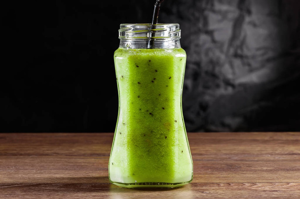 Smoothies in a glass jar of kiwi, green apple, lime, mint and avocado on a wooden table. The concept of a healthy diet, detox. - Фото, изображение