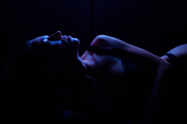 Giovane ragazza sexy in una bella biancheria intima di pizzo erotico sdraiato isolato su uno sfondo nero
 - Foto, immagini
