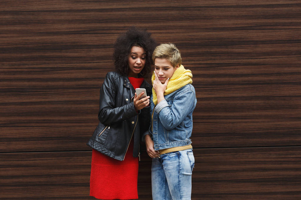 verblüffte Freundinnen mit Smartphone im Freien - Foto, Bild