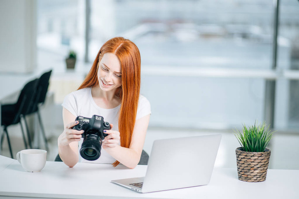 vörös hajú lány fotós nézi képeket a kamera. - Fotó, kép