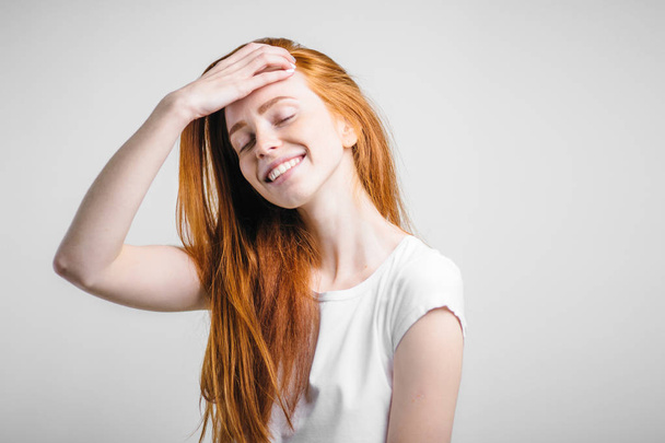 girl with freckles smiling with closed eyes touching her red hair - Photo, image