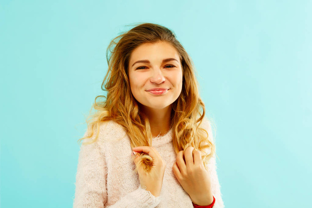Young happy woman in warm sweater over blue background - Fotoğraf, Görsel