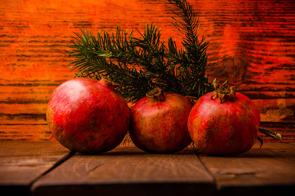 juicy pomegranate on wooden boards. fresh green fir branch. ripe pomegranate on wooden boards. - 写真・画像