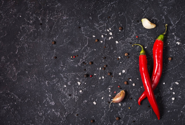 Red hot chili pepeprs and peppercorns on black stone background, top view - Foto, immagini