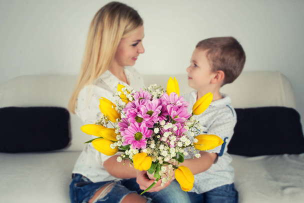 Son gives his beloved mother a beautiful bouquet of tulips.The concept of the celebration,women's day. - Zdjęcie, obraz