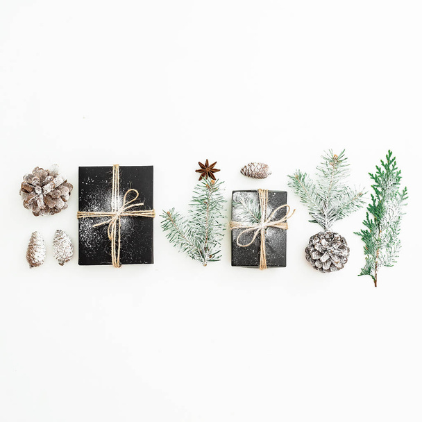 Marco de Navidad hecho de elegantes cajas de regalo negras, ramas de abeto y conos de pino sobre fondo blanco. Concepto de año nuevo. Acostado. Vista superior
 - Foto, imagen