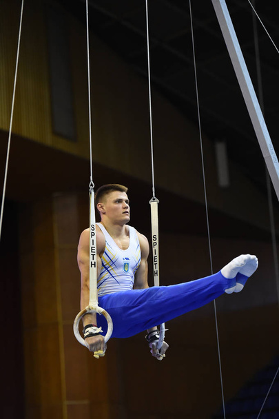 Male gymnast performing on stationary gymnastic rings - Фото, изображение