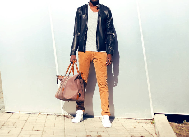 Fashion man in a black leather jacket with bag in the city - Φωτογραφία, εικόνα