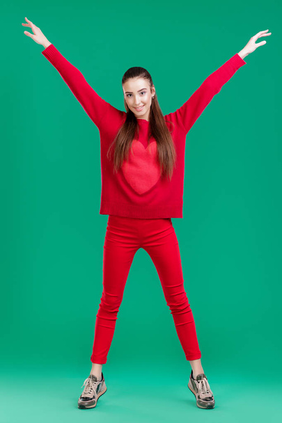 woman in red sweater on green background - Foto, afbeelding