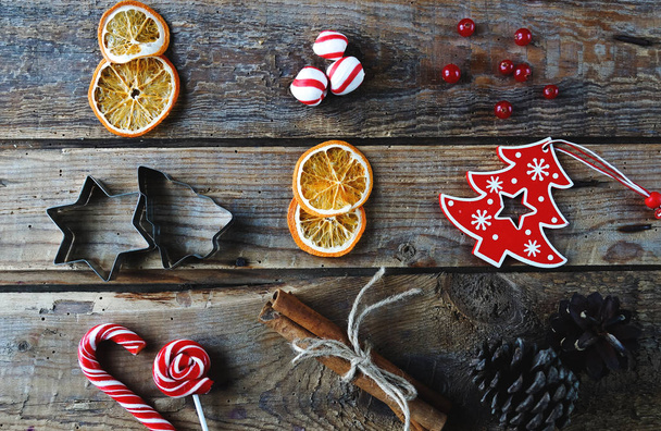 Decoración para el hogar de Navidad plana, naranjas secas, canela, caramelos, juguetes sobre fondo de madera rústica
 - Foto, Imagen