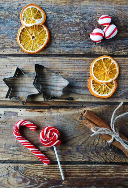 Christmas flat lay home decor, dry oranges, cinnamon, candies, toys on rustic wooden background - Fotó, kép