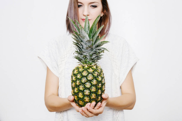 girl holds pineapple. Young woman with pineapple. fruits and vegetables in their hands. pineapple on the head. - Foto, Imagen