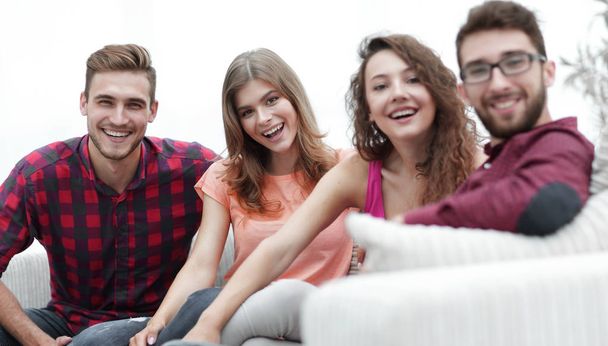 group of cheerful friends sitting on sofa - Фото, изображение