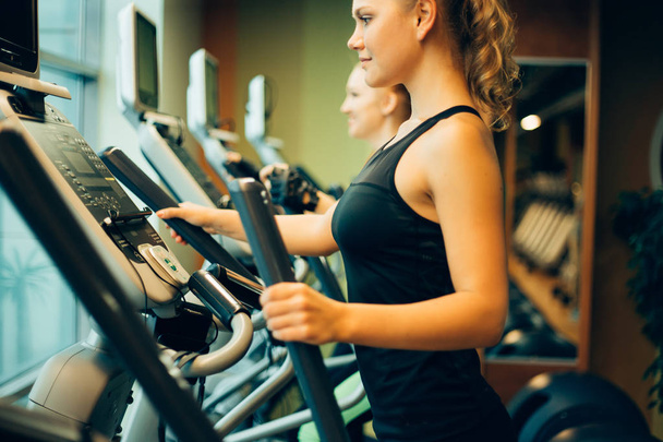 woman exercising on cross trainer machines. - Photo, image